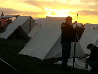 Reenactor cleaning rifle as the sun rises.